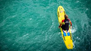 Birds eye view of an RNLI lifeguard sitting on a paddleboard at sea.